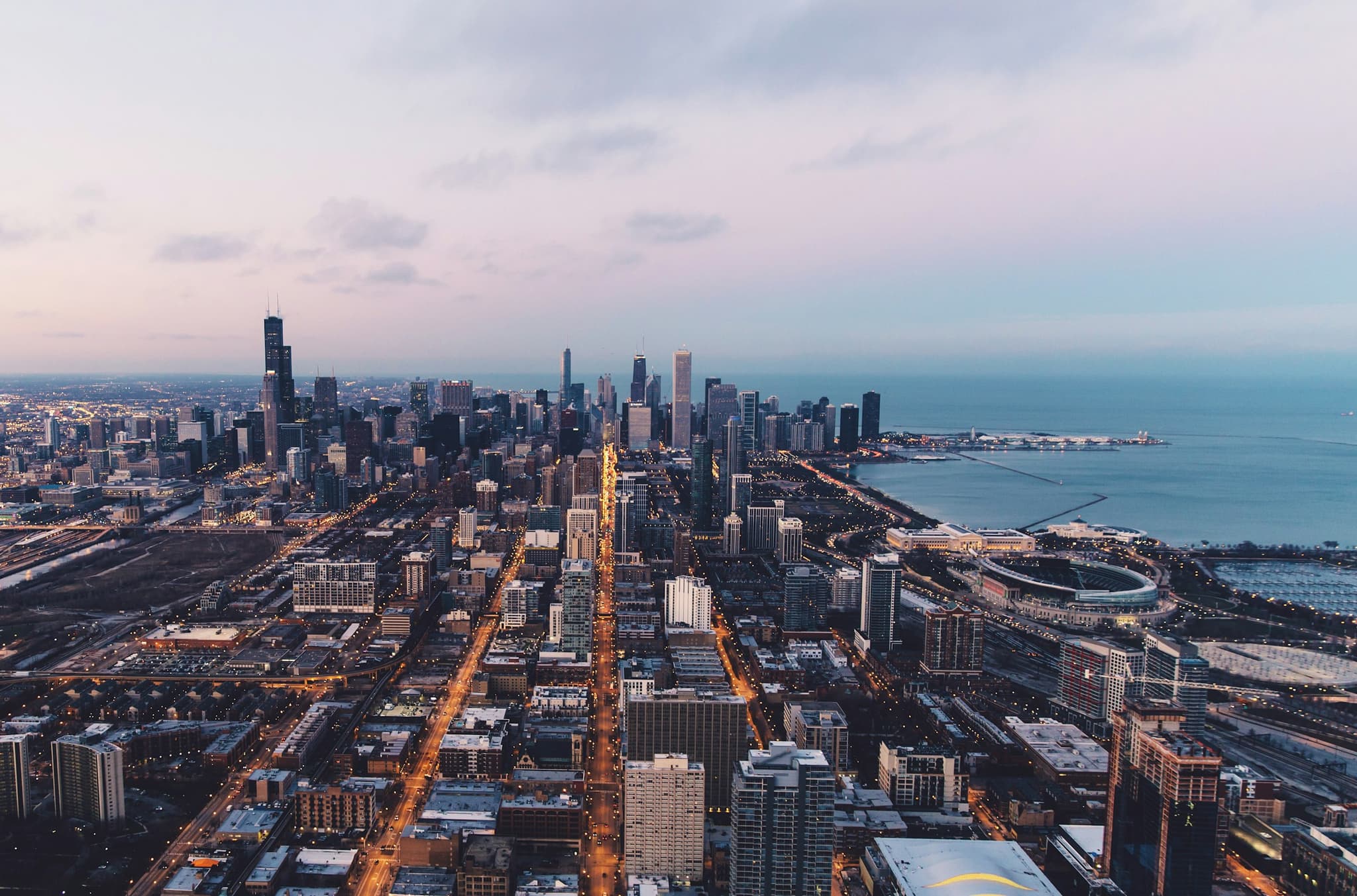 Chicago's neighborhoods from the air at dusk, streets running to the lake