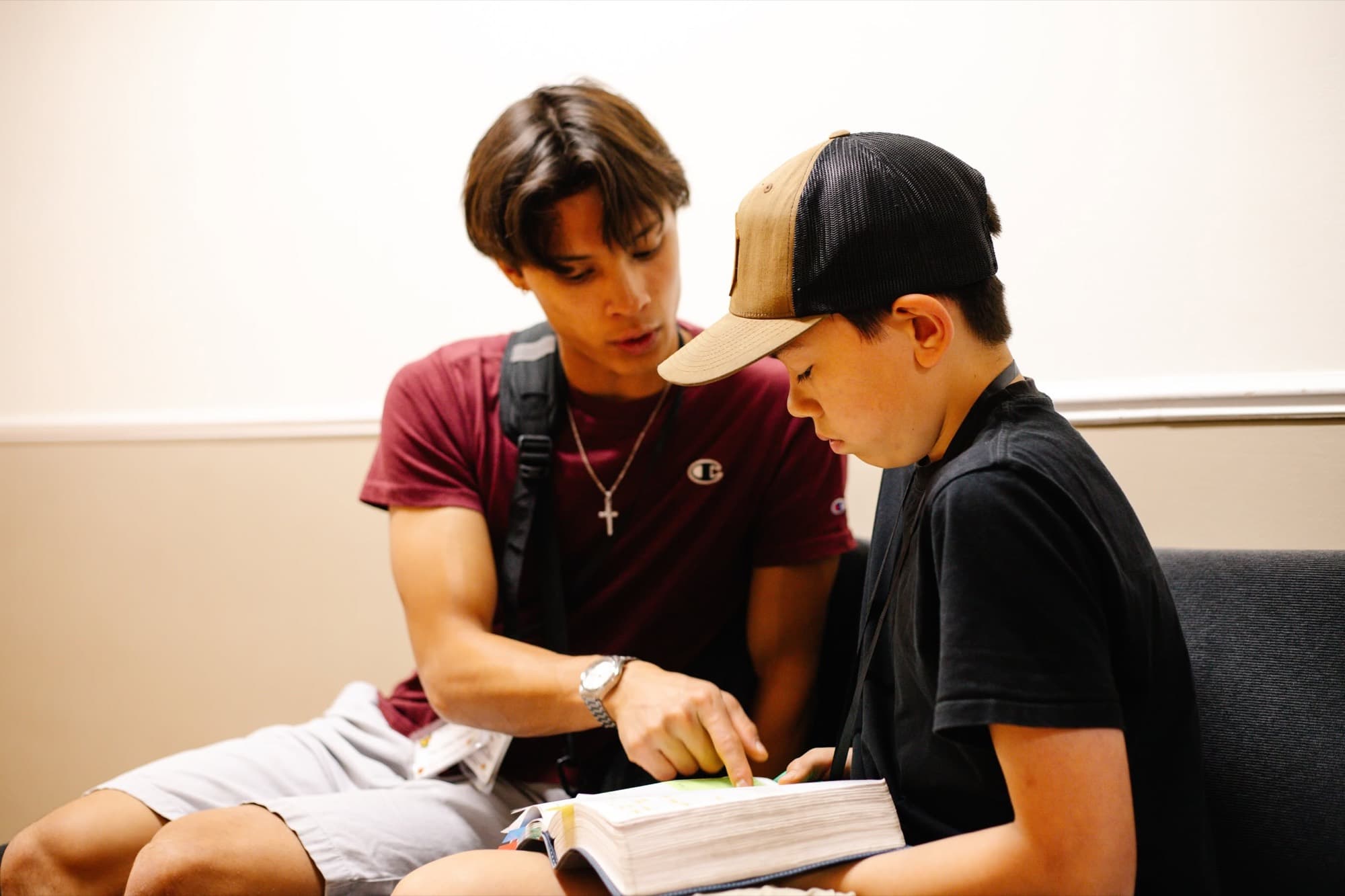 Two teenage boys read an open book together